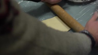 Rus mantı mankenleri. Yakın plan. Erkek eller, hamuru ahşap bir oklava ile masaya yuvarlar.