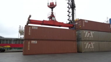 Vladivostok, Rusya - Vladivostok 'taki ticari konteynır terminali. Yakın plan. Büyük bir vinç bir konteynırı kaldırır ve kargo gemisine yükler..