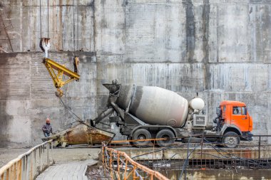 Autumn, 2016 - Magadan, Russia - Construction of the Ust-Srednekanskaya hydroelectric station. A concrete mixer truck stands at the dam under construction and delivers concrete mortar to the builders. clipart