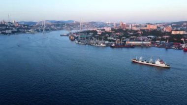 Yukarıdan bak. Beyaz bir ticaret gemisi Golden Horn boyunca limana doğru yelken açıyor. Vladivostok 'ta gün batımında ticari limanlar.