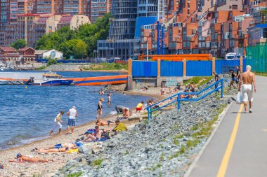 2016 Yazı - Vladivostok, Rusya - Vladivostok 'taki Fedorov Körfezi' nin su bölgesi. İnsanlar şehir merkezindeki bir halk plajında yüzüyor ve güneşleniyor. Güzel konut binaları ve mavi deniz manzarasına karşı.