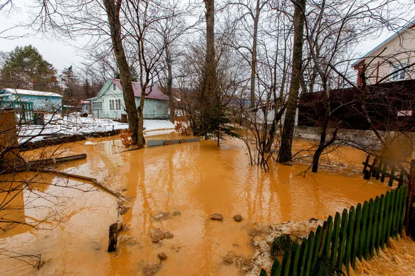 Ecological catastrophy. The stream of a dirty brown river flows along the ground in a holiday village. The holiday village is buried in a muddy mudflow