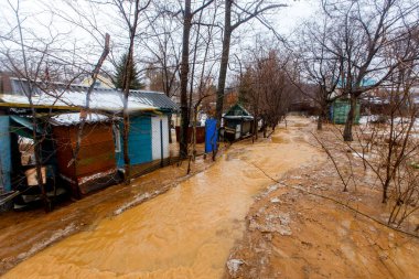 Ekolojik felaket. Kirli kahverengi bir nehrin deresi bir tatil köyünde zemin boyunca akar. Tatil köyü çamurlu bir akıntıya gömüldü.