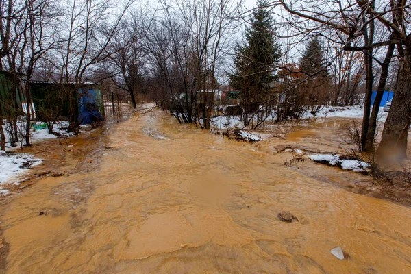 Ecological catastrophy. The stream of a dirty brown river flows along the ground in a holiday village. The holiday village is buried in a muddy mudflow