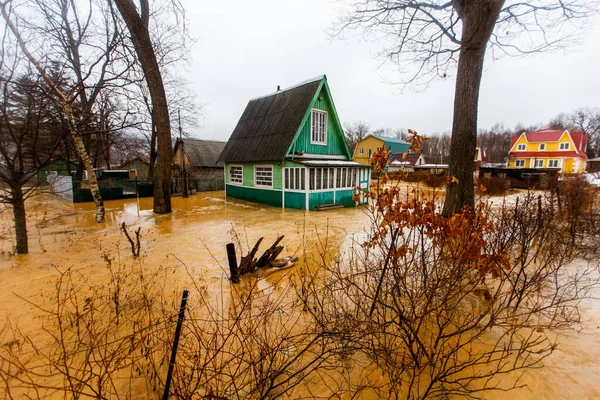 Ecological catastrophy. The stream of a dirty brown river flows along the ground in a holiday village. The holiday village is buried in a muddy mudflow