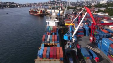 Vladivostok, Rusya - Yaz, 2020 - Konteynırlarla dolu bir ticaret gemisi limanın rıhtım duvarında duruyor ve demirlemeyi bekliyor. Vladivostok konteyner terminalinin bölgesi. Yukarıdan görüntüle.
