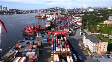 Vladivostok, Rusya - 2020 yazı - Vladivostok konteyner terminalinin bölgesi. Yukarıdan bak. Şehir merkezinin arka planına karşı deniz kenarındaki küçük bir konteynır deposunun üzerinden uçuyor.