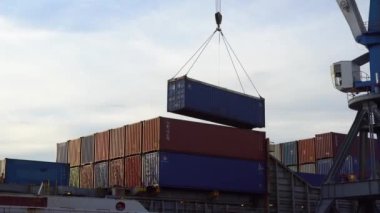 Vladivostok, Rusya - 2020, yaz - Vladivostok ticari deniz limanında çalışıyor. Büyük bir vinç, konteynırlarla dolu bir ticaret gemisine metal bir konteynır yüklüyor.