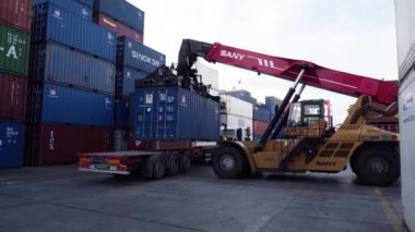 Vladivostok, Rusya, 2020 - Limandaki Vladivostok deniz konteynırı terminali operasyonu. Bir istifçi büyük bir konteynırı bir kamyona yüklüyor. Bir konteynırı arabaya yüklemek.