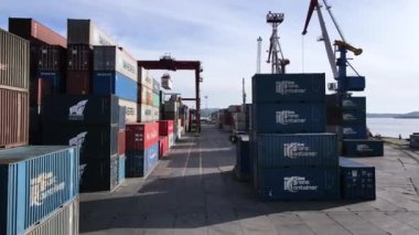 Vladivostok, Rusya - 2020, Yaz - Vladivostok Ticari Deniz Konteynırı Limanı. Kamera limandaki uzun konteynırların arasında uçuyor. Konteynırlar yükleniyor ve boşaltılıyor