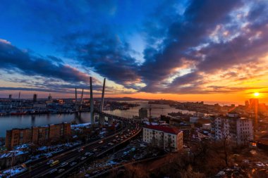 Vladivostok 'ta gün batımı parlıyor. Renkli bir günbatımında Altın Köprü. Altın Boynuz Körfezi