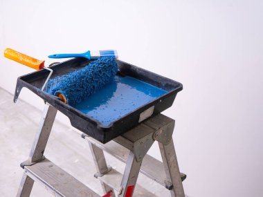 Yuvarlak silindirli ve mavi boya dolu fırçalı Cuvette merdiven üzerinde duruyor.