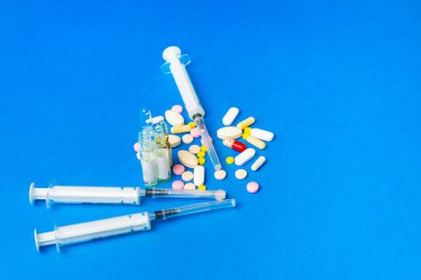 İlaçları, tabletleri, ampulleri ve mavi arka planda şırıngayı kapat. Grip ve virüs tedavisi kavramı.