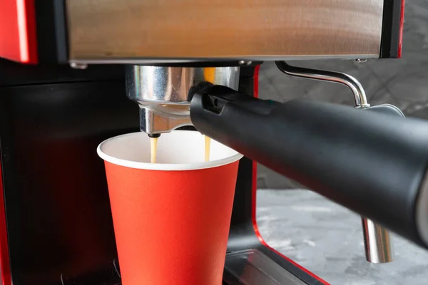 Máquina de café rojo llena una taza de papel rojo. Café para llevar. Primer plano — Foto de Stock