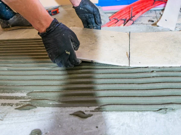 Skilled worker installing the ceramic tiles on the floor Worker making flooring on the construction site of the new apartment — Stock Photo, Image