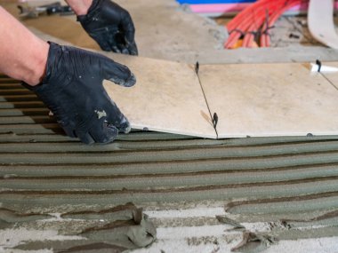 Seramik fayansları döşeyen usta işçiler yeni apartmanın inşaat alanında döşeme yapıyor.