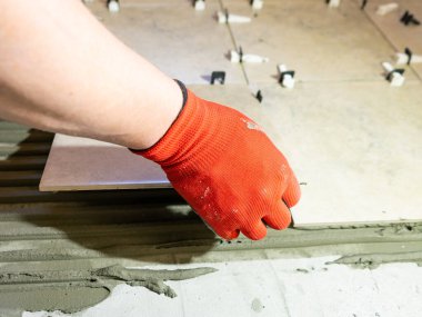 Seramik fayanslar yerleştiriliyor. Fayansları yapıştırıcı malzeme yatak örtüsüne yerleştiriliyor. Yakın plan.