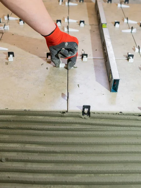 Workers are using plastic clamps and wedges to leveling the ceramic tile on the floor. Tile leveling system. — Stock Photo, Image