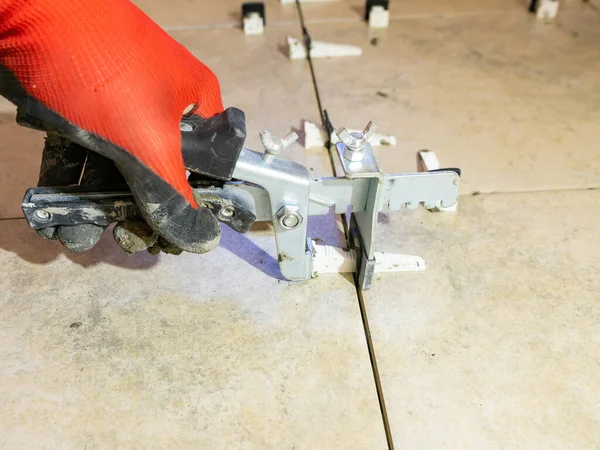 A worker is leveling the ceramic tile with wedges and clips. Tile leveling system — Stock Photo, Image