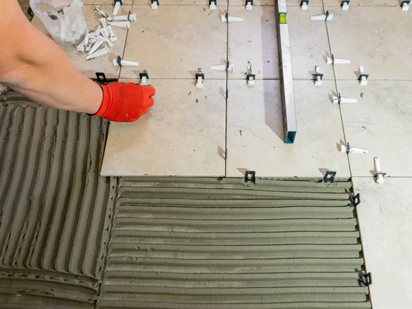 Workers are using plastic clamps and wedges to leveling the ceramic tile on the floor. Tile leveling system. — Stock Photo, Image