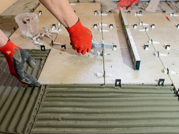 A worker is leveling the ceramic tile with wedges and clips. Tile leveling system — Stock Photo, Image