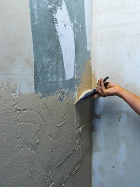 İşçilere göre ev geliştirme. Spatulalı bir el. İşçi malası macunu bitiren macunla duvarda.