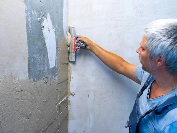 House improvement by worker. Hand with a spatula. Worker trowels putty on wall with finishing putty