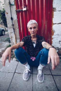 Sarışın genç kadın eski binanın yanındaki sokakta oturuyor. 