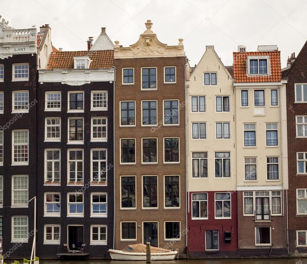 row of typical crooked houses on canal in Amsterdam