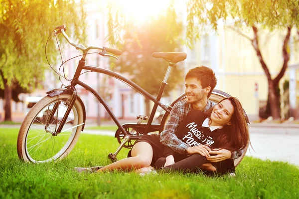 Gelukkige lachende jonge paar liggen in een park in de buurt van een vintage fiets — Stockfoto