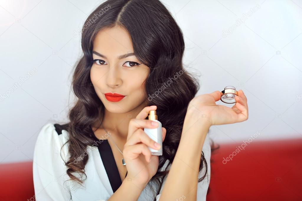 Woman with perfume, young beautiful girl holding bottle of perfu