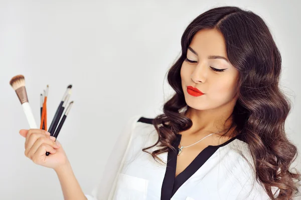 Hermosa mujer con pinceles de maquillaje cerca de su cara —  Fotos de Stock