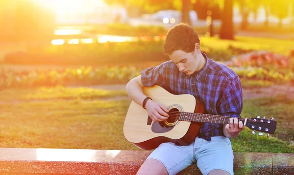 Praxi v hraní na kytaru. pohledný mladý muž hraje na acou — Stock fotografie