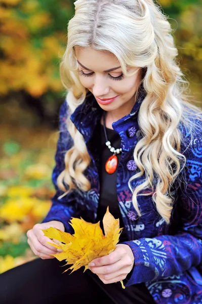 Mujer joven con hojas de otoño en la mano y caen gar arce amarillo — Foto de Stock