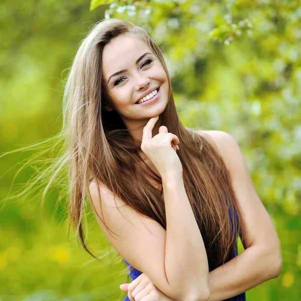 Jeune femme souriante posant dans un parc verdoyant — Photo