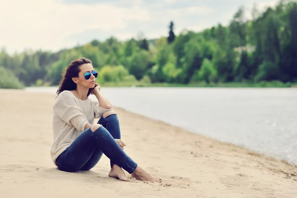 Sexig ung kvinna sitter på en strand utomhus mode porträtt — Stockfoto