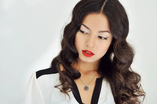 Menina bonita com lábios vermelhos e cabelos negros encaracolados em branco backg — Fotografia de Stock