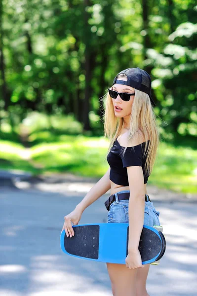 Красивая и модная молодая женщина позирует со скейтбордом — стоковое фото