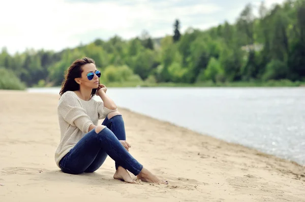 Mladá krásná žena, sedící u pláže — Stock fotografie