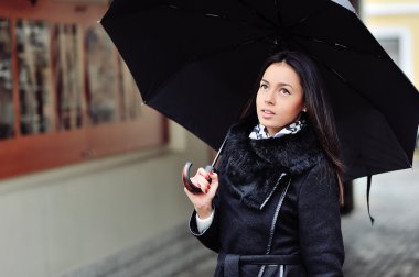 Kadın siyah şemsiyesi altında