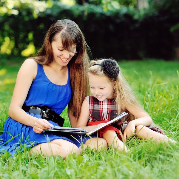 Küçük kız ve annesi bir yaz parkında kitap okuyorlar. — Stok fotoğraf