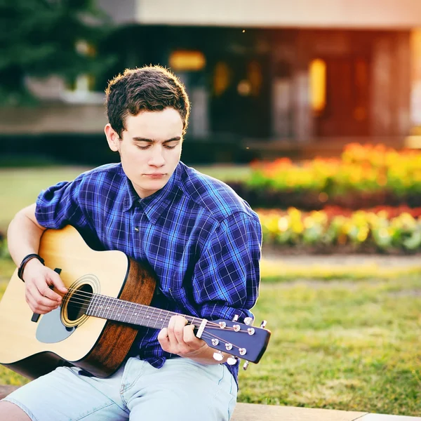 Mladá bederní muž hrát na kytaru v parku — Stock fotografie