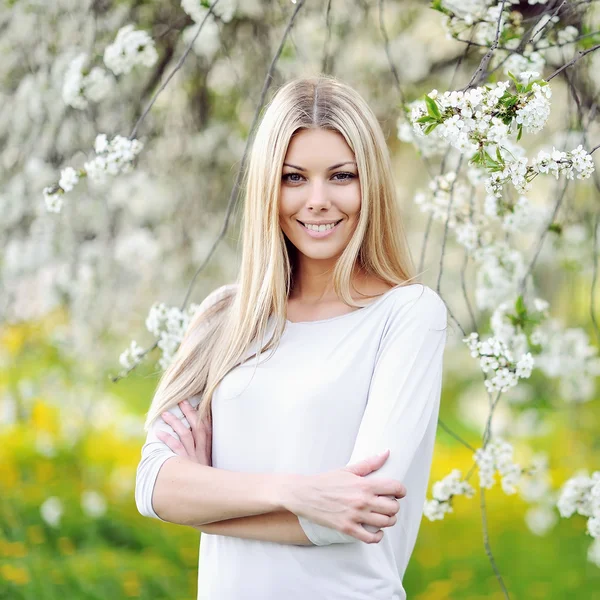 Vacker flicka i blommande träd på våren — Stockfoto
