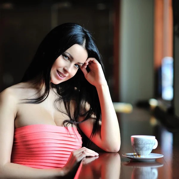 Hermosa chica sentada en el restaurante con una taza de té o co — Foto de Stock