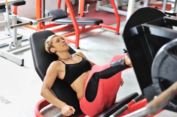 Passar kvinnan utbildning ben på en benet simulator på gymmet — Stockfoto
