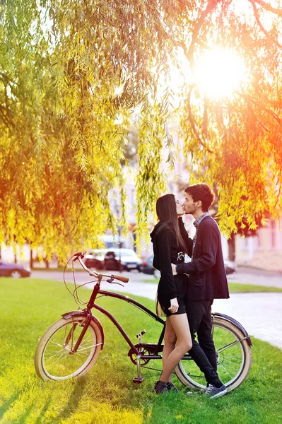 Jong koppel in een park in de buurt van een vintage fiets kussen — Stockfoto