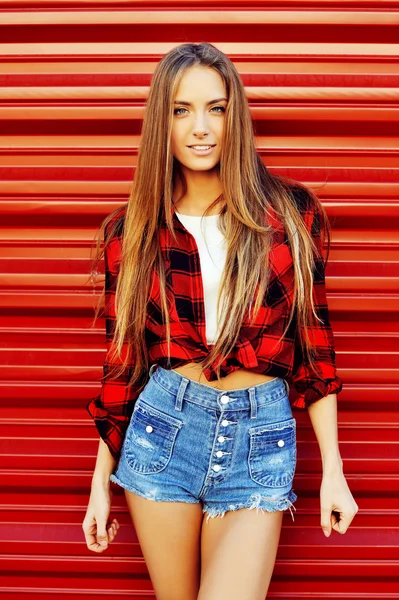 Mujer joven moderna posa frente al fondo de la pared roja. Sexy w — Foto de Stock