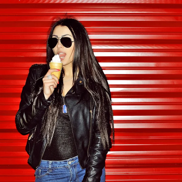 Sexy brunetka lízání zmrzliny na pozadí červené zdi — Stock fotografie