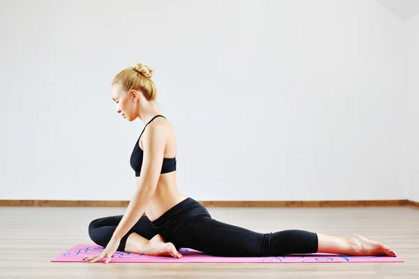 Young slim sports woman stretching indoors — Stock Photo, Image