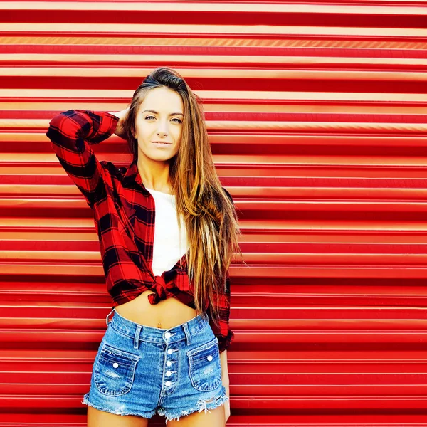Atractiva joven posando cerca de una pared roja - copyspace —  Fotos de Stock